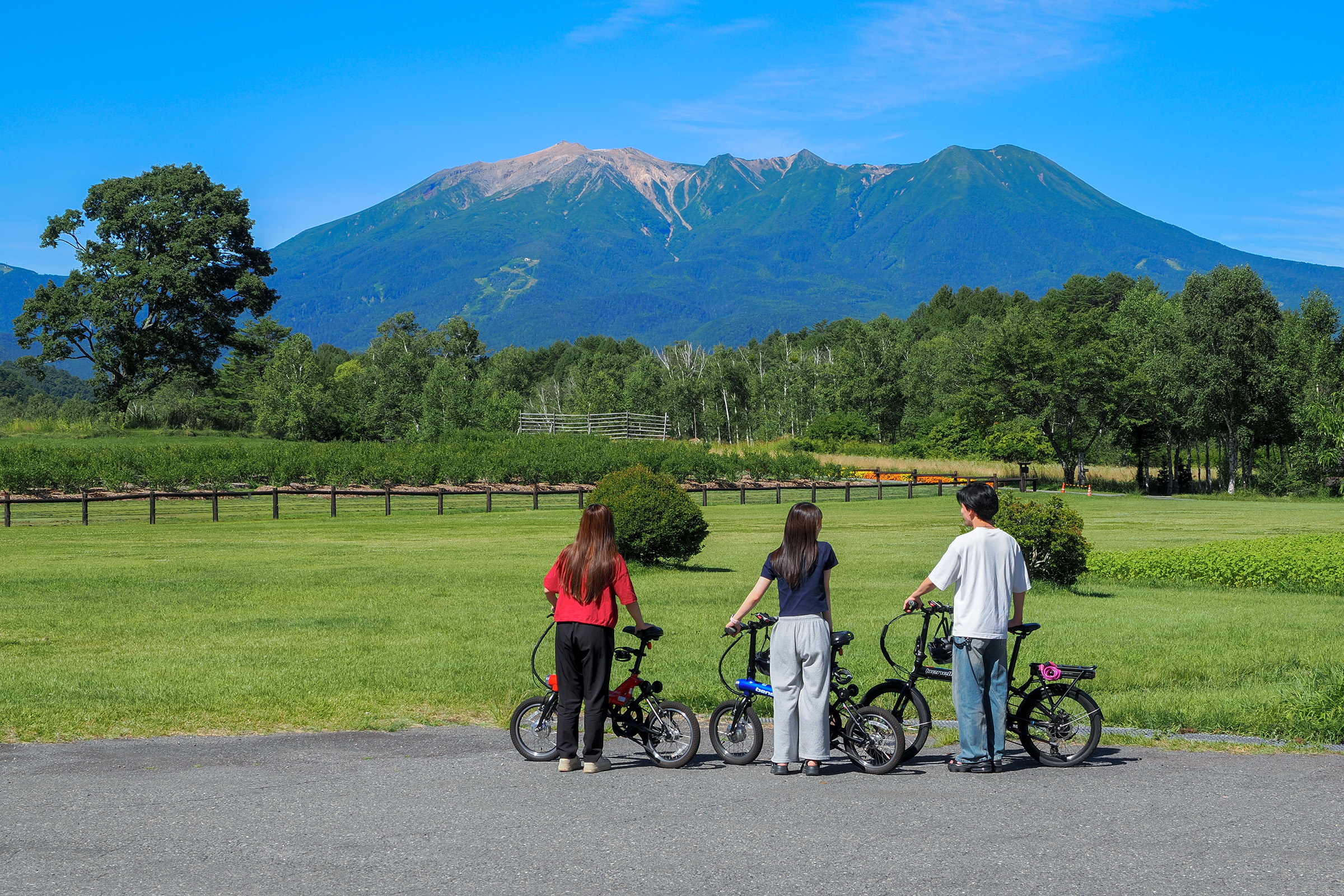 電動自転車を楽しむ若者と御嶽山