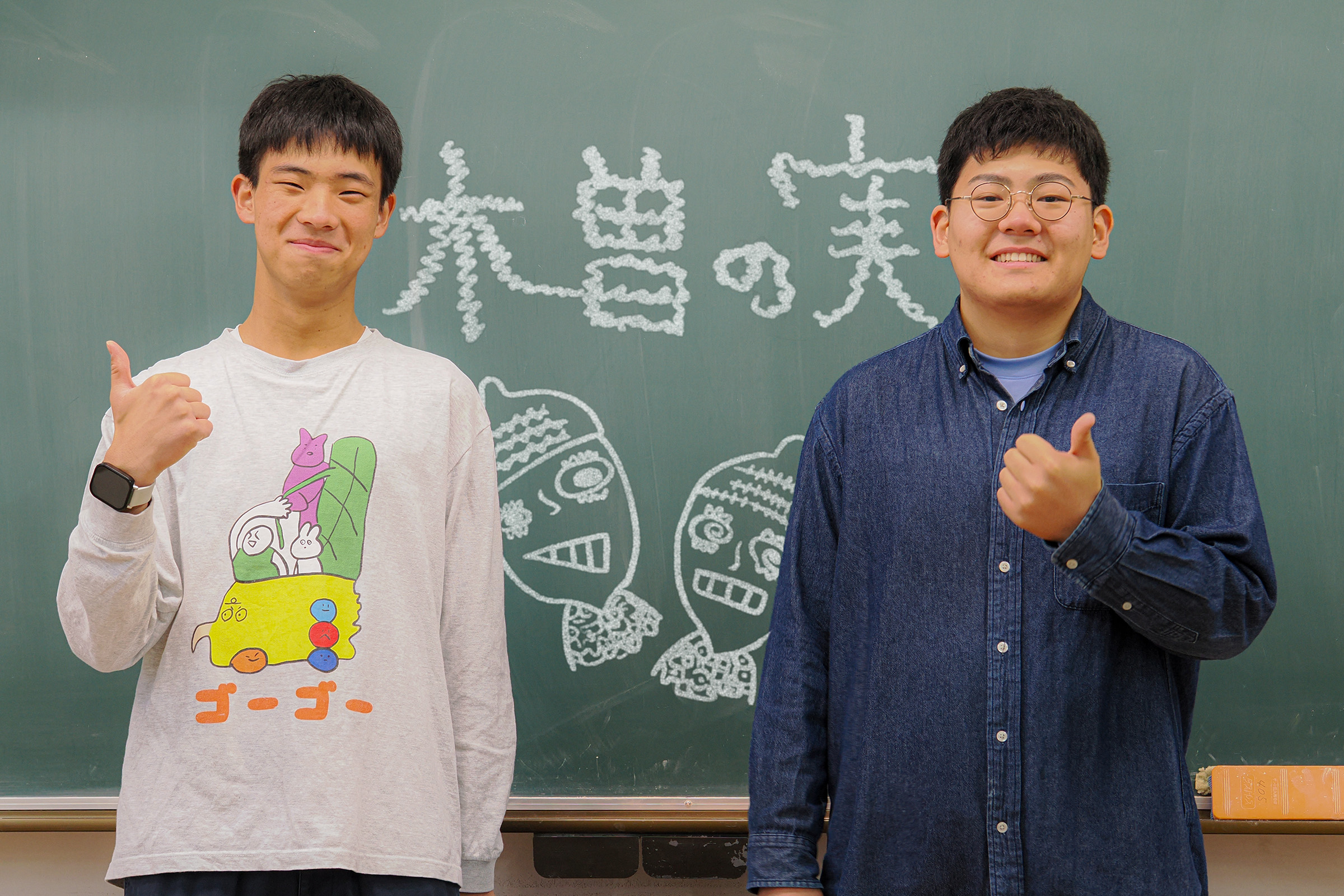 黒板の前でサムアップ、木曽の実をよろしくお願いいたします