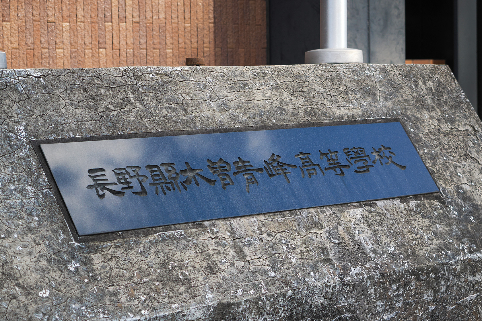 青空が反射する木曽青峰高校の銘板