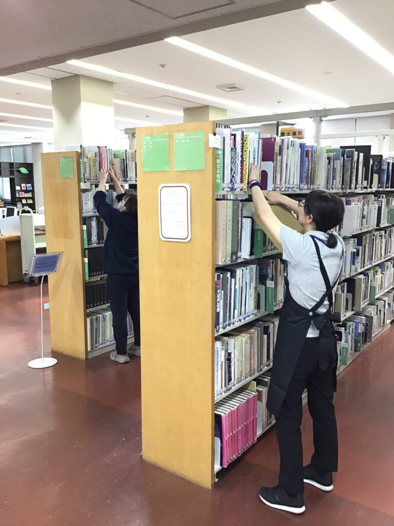 書架で配列点検の作業をしている職員の写真
