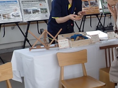 松本地域で製作された長野県産材木工品の譜面台と、貝殻の形の木工アート作品の写真。